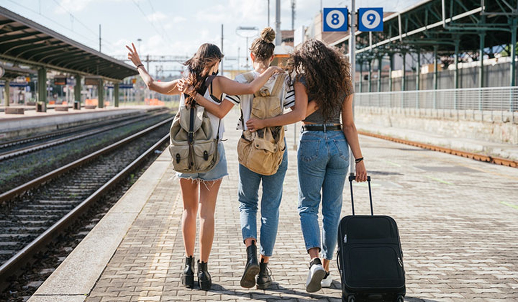 Drie vriendinnen met bagage op een station