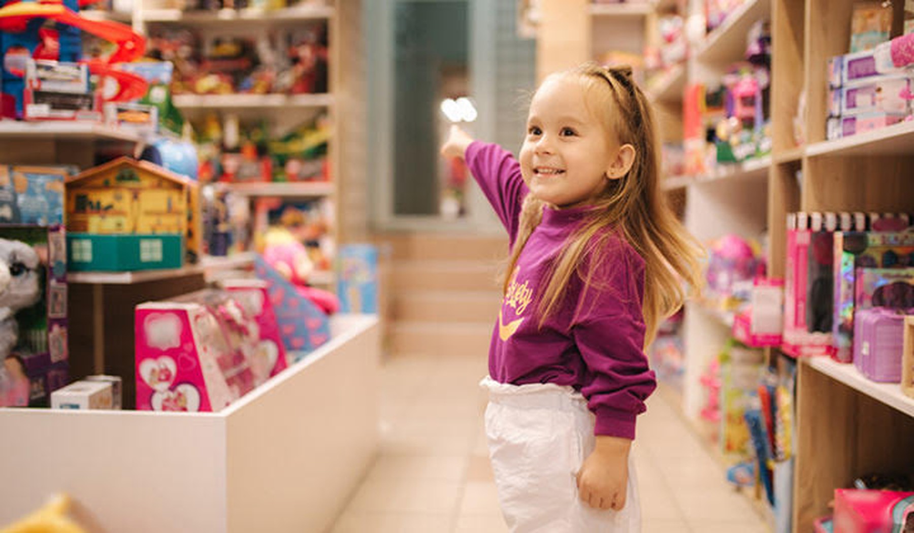Een enthousiast meisje in een speelgoedwinkel