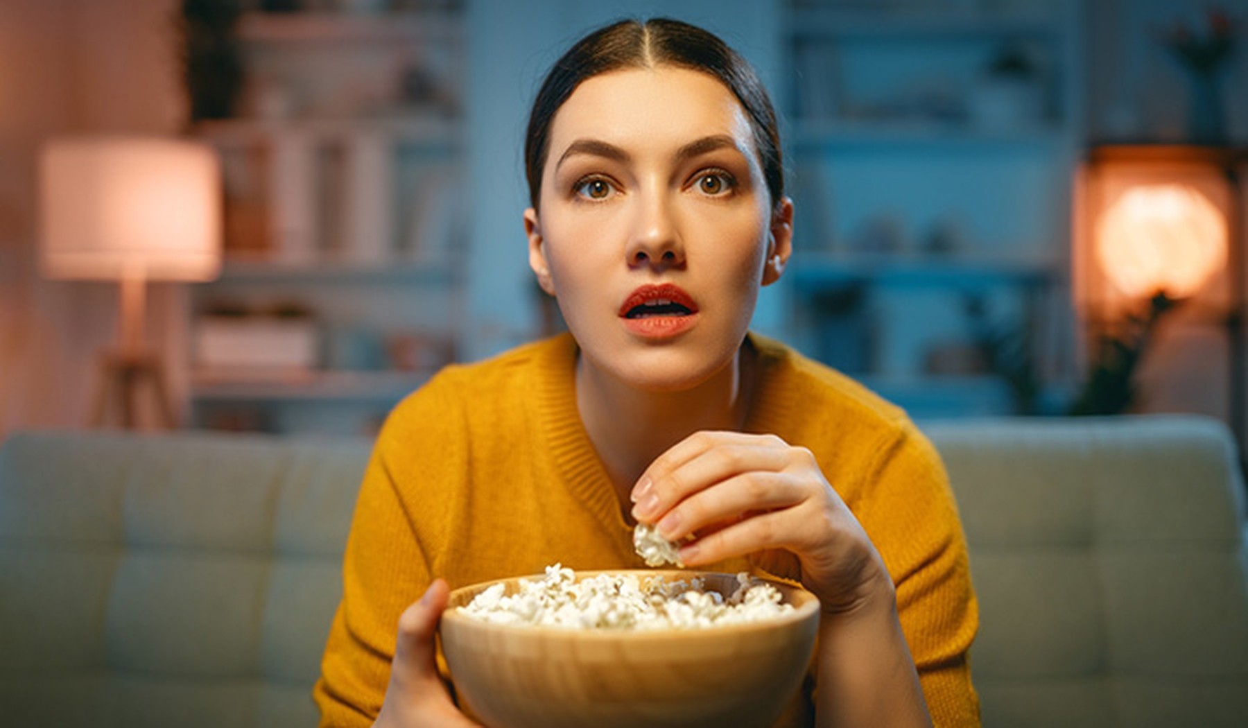 Vrouw kijkt tv en eet popcorn huiskamer