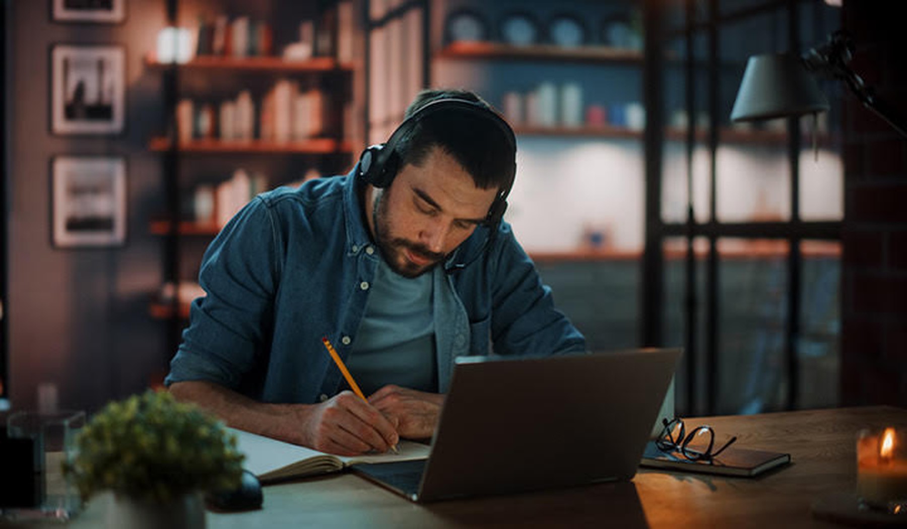 Man met koptelefoon studeert achter laptop