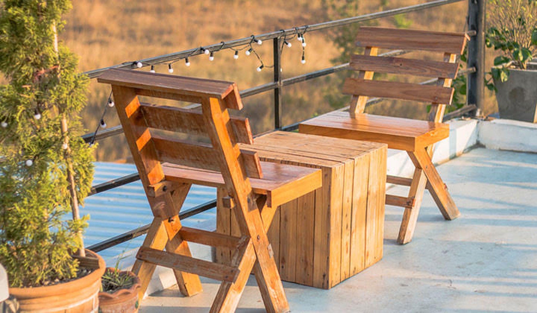 houten klapstoelen en tafel op balkon met lichtjes