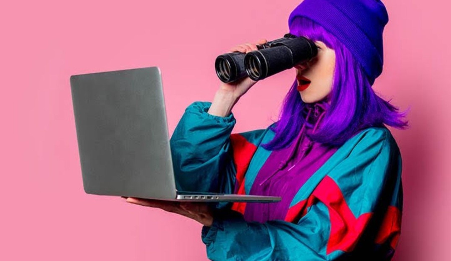 Vrouw met paars haar kijkt door verrekijker naar laptop