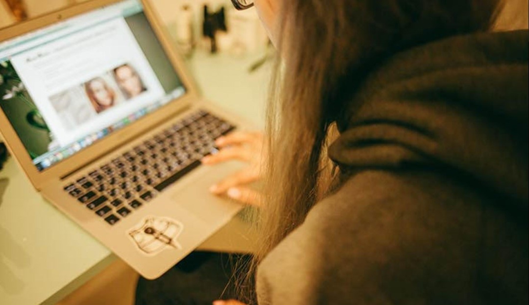 Over-de-schouder-shot van een meisje die op haar laptop kijkt