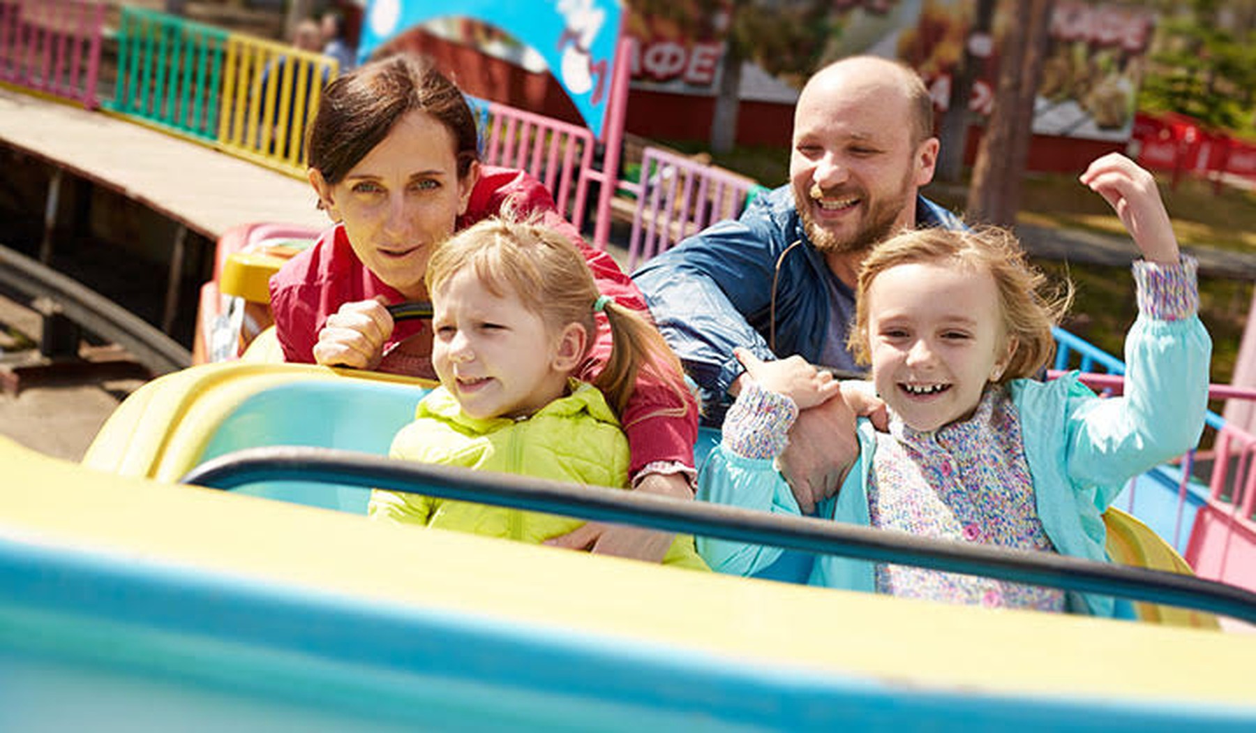 Een familie met jonge kinderen zit samen in de kleurrijke achtbaan