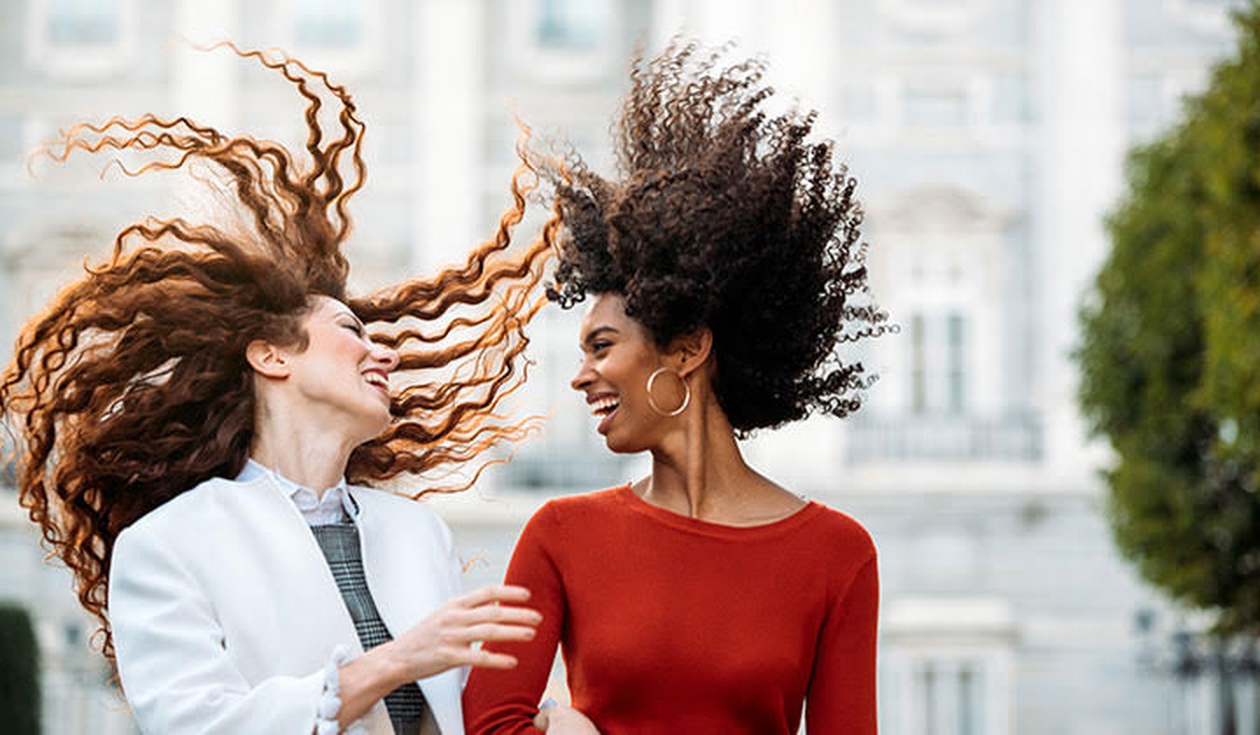 Twee vrolijke vrouwen met hun haren in de lucht