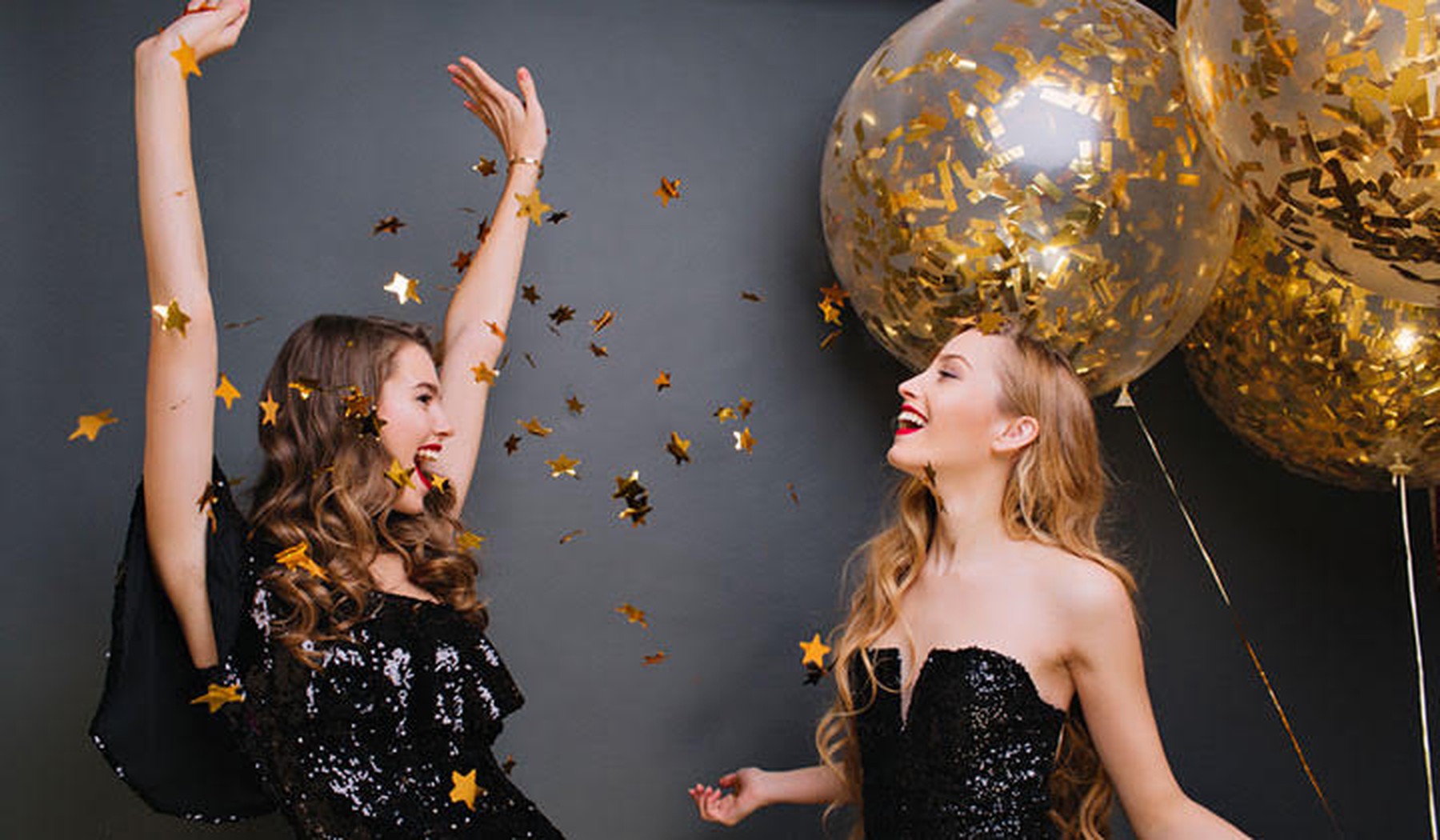 Twee vrolijke vrouwen in feestkleding en met ballonnen op de achtergrond
