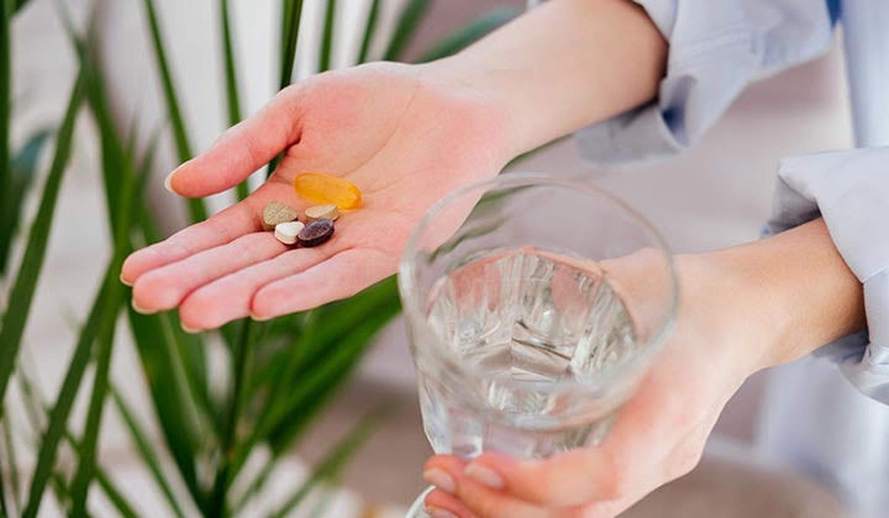 Vrouw houdt supplementen en glas met water vast