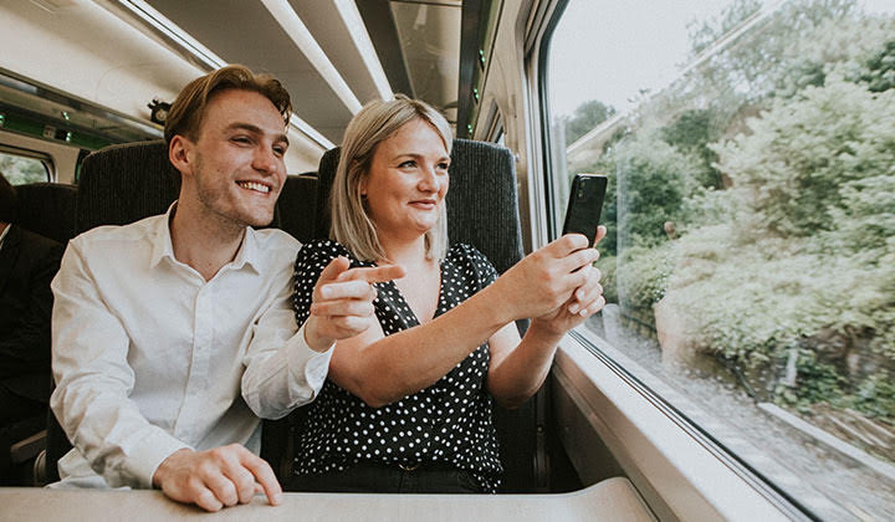 Een man en vrouw naast elkaar in de trein, naar buiten kijkend