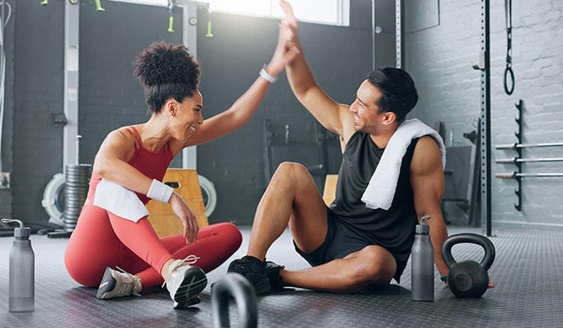 Een man en vrouw die elkaar in de sportschool een high five geeft