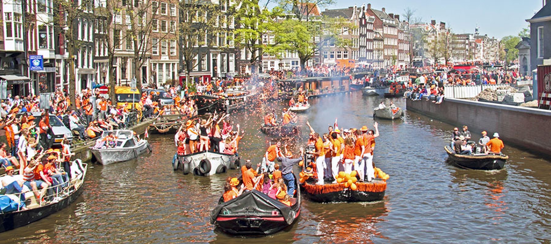 Amsterdamse gracht met bootjes tijdens Koningsdag
