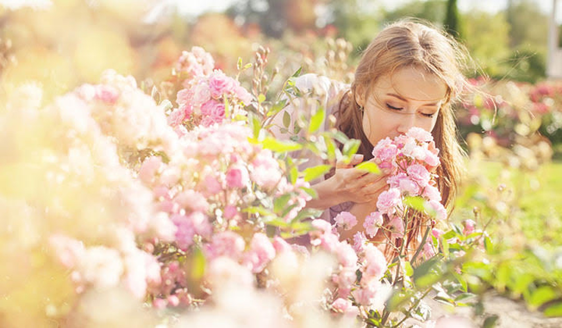 Een vrouw die buiten aan bloemen ruikt