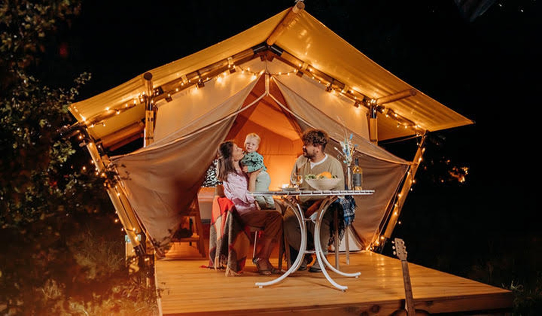 Een gezin die de avond doorbrengt voor de tent van een glamping