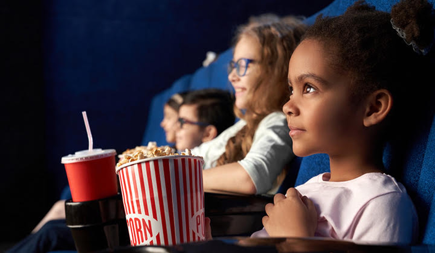Kinderen die met popcorn en frisdrank in de bios een film kijken