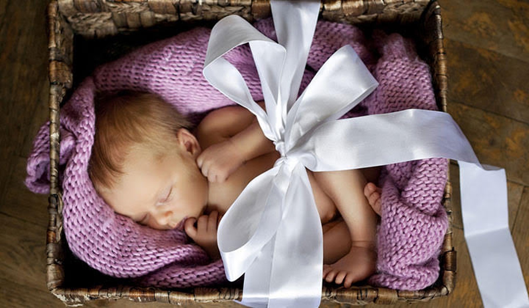 Een slapende baby in een giftbox met strik erom