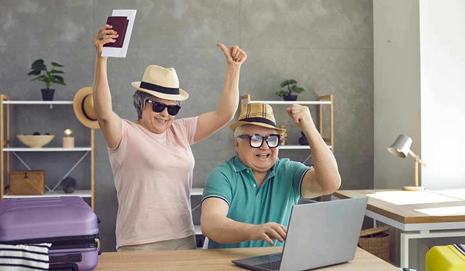 Een blij senior echtpaar in vakantie outfit achter de laptop