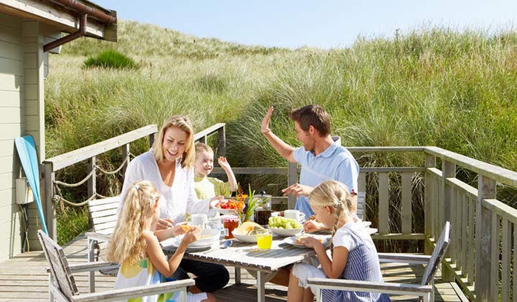 Een gezin dat voor een vakantiehuisje in de duinen eet